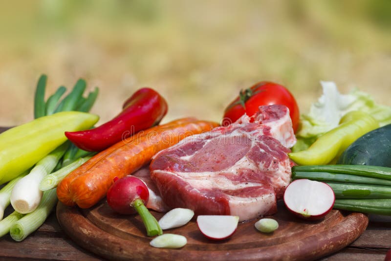 Комплект свежих овощей и сырцового мяса стейка на деревянной доске стоковая фотография Комплект свежих овощей и сырцового мяса стейка на деревянной доске стоковая фотография