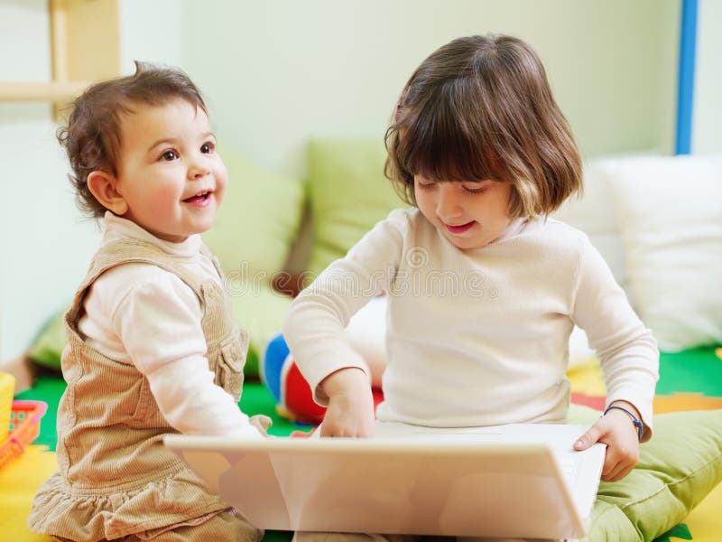 Female toddler and 2-3 years old girl playing with pc in kindergarten. Horizontal shape. Female toddler and 2-3 years old girl playing with pc in kindergarten. Horizontal shape