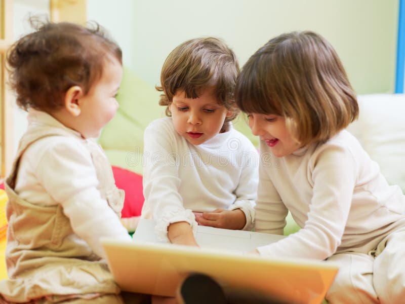 Female toddler and 2-3 years old girls playing with pc in kindergarten and smiling. Horizontal shape. Female toddler and 2-3 years old girls playing with pc in kindergarten and smiling. Horizontal shape