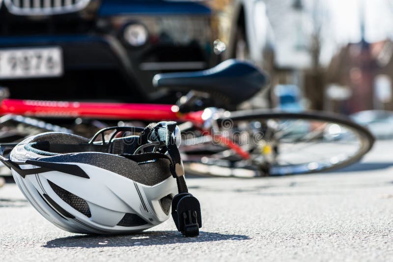 Close-up of a bicycling helmet fallen on the asphalt next to a bicycle after car accident on the street in the city. Close-up of a bicycling helmet fallen on the asphalt next to a bicycle after car accident on the street in the city