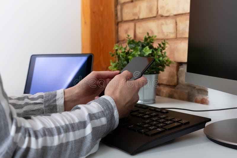 Конец-вверх женских рук используя современный умный телефон пока работающ на офисе с компьютером, текстовым сообщением коммерсант стоковые фотографии rf Конец-вверх женских рук используя современный умный телефон пока работающ на офисе с компьютером, текстовым сообщением коммерсант стоковые фотографии rf