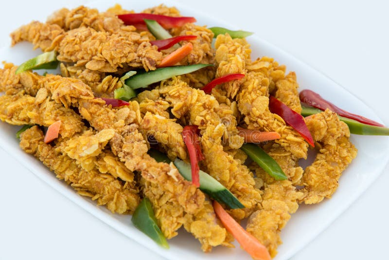 Конец-вверх очень вкусных хрустящих прокладок куриной грудки жареной курицы на белой плите, на белой таблице с перцем, огурцами и стоковая фотография rf Конец-вверх очень вкусных хрустящих прокладок куриной грудки жареной курицы на белой плите, на белой таблице с перцем, огурцами и стоковая фотография rf