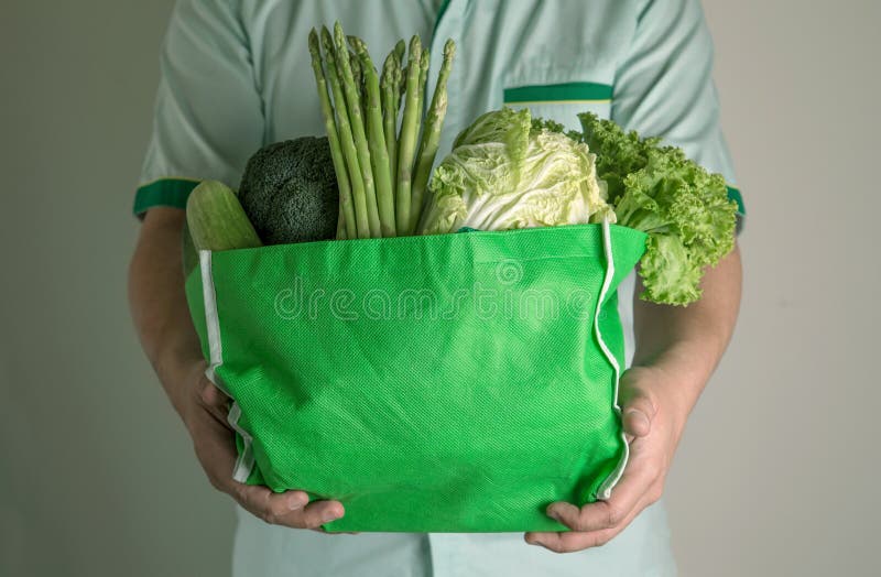 конец вверх по руке держа зеленую продуктовую сумку смешанного органические зеленые овощи, здоровый органический зеленый поход в стоковые изображения
