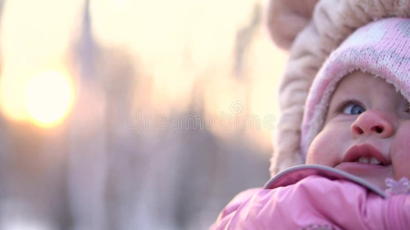 Конец-вверх ребенка усмехаясь в зиме Счастливый любопытный ребенок в розовом комбинезоне в предпосылке зимы парка акции видеоматериалы Конец-вверх ребенка усмехаясь в зиме Счастливый любопытный ребенок в розовом комбинезоне в предпосылке зимы парка акции видеоматериалы