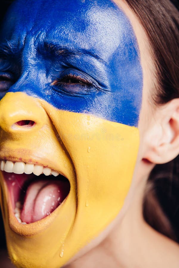 Конец по представлению молодой женщины с цветным украинским флагом на коже кричащей и плакать стоковые изображения rf