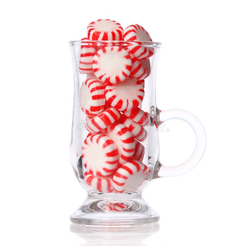 Peppermint candy in glass isolated on white. Red striped mint Christmas candy, macro. Peppermint candy in glass isolated on white. Red striped mint Christmas candy, macro