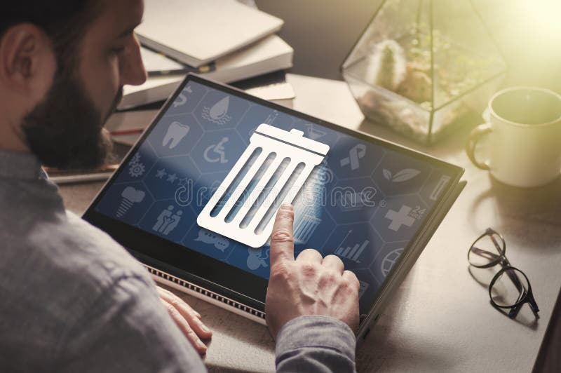 Man with laptop on his desk. He presses on the icon of trash can. The concept of erase contacts, files, informations. Man with laptop on his desk. He presses on the icon of trash can. The concept of erase contacts, files, informations