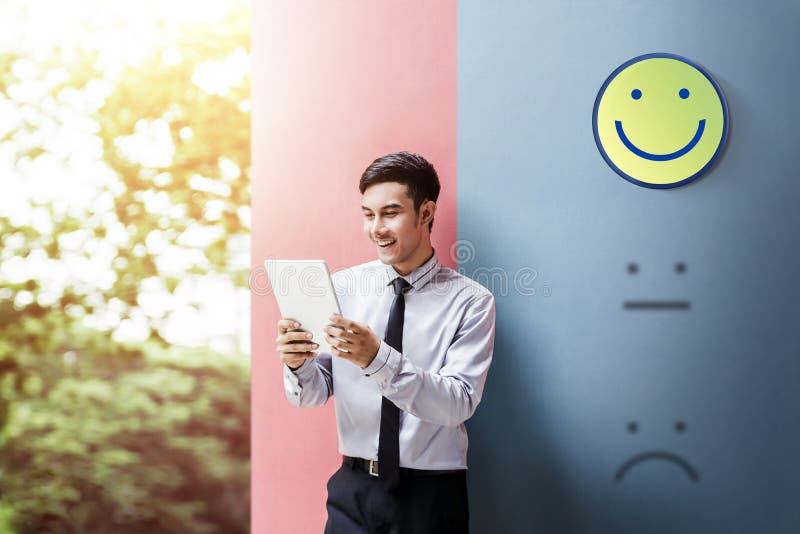 Customer Experience Concept, Happy Businessman Enjoying on digital Tablet with Smiley Face Rating for a Satisfaction Survey. Customer Experience Concept, Happy Businessman Enjoying on digital Tablet with Smiley Face Rating for a Satisfaction Survey