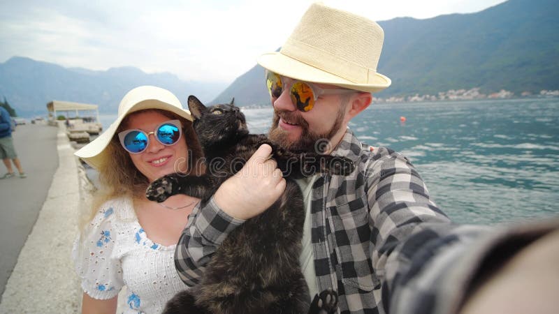 концепция поездок и новый опыт. счастливая пара с котом, которые селфи на заднем плане залива
