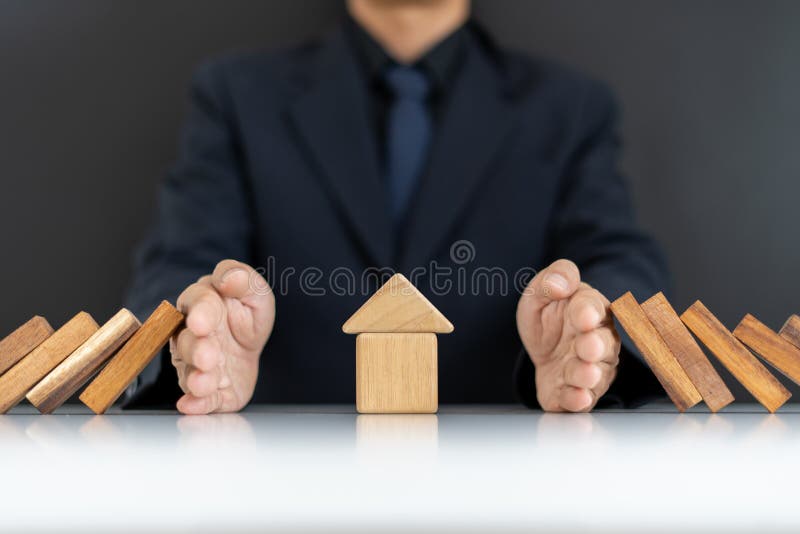 The concept of home insurance. The hands of businessmen or homeowners that are blocking Domino fall from home. Maintaining security and home safety. The concept of home insurance. The hands of businessmen or homeowners that are blocking Domino fall from home. Maintaining security and home safety.