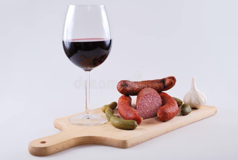 Копченые bratwurst мяса и стекло красного вина стоковое фото rf Копченые bratwurst мяса и стекло красного вина стоковое фото rf