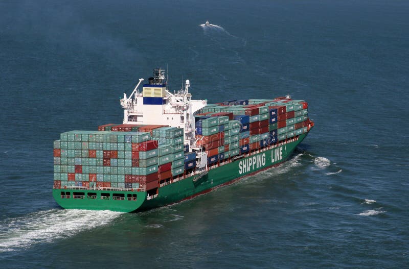 A fully loaded container or cargo ship leaves port and sails away into the distance. A fully loaded container or cargo ship leaves port and sails away into the distance.
