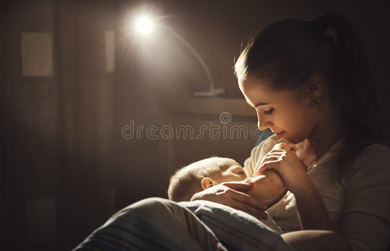 Breastfeeding. mother feeding a baby breast in bed dark night. Breastfeeding. mother feeding a baby breast in bed dark night