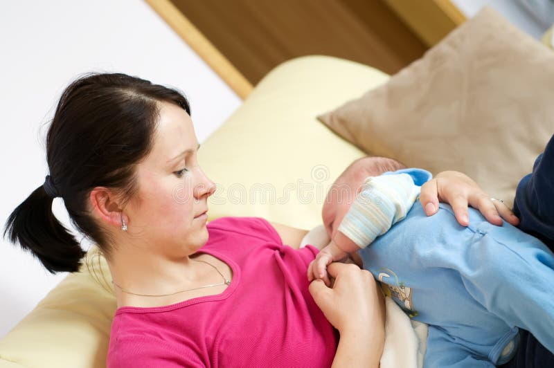 Mother breast feeding her newborn on sofa. Mother breast feeding her newborn on sofa.
