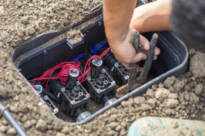 Drip irrigation valve box with valves for water plants with automatic watering system. Selective focus. Drip irrigation valve box with valves for water plants with automatic watering system. Selective focus.