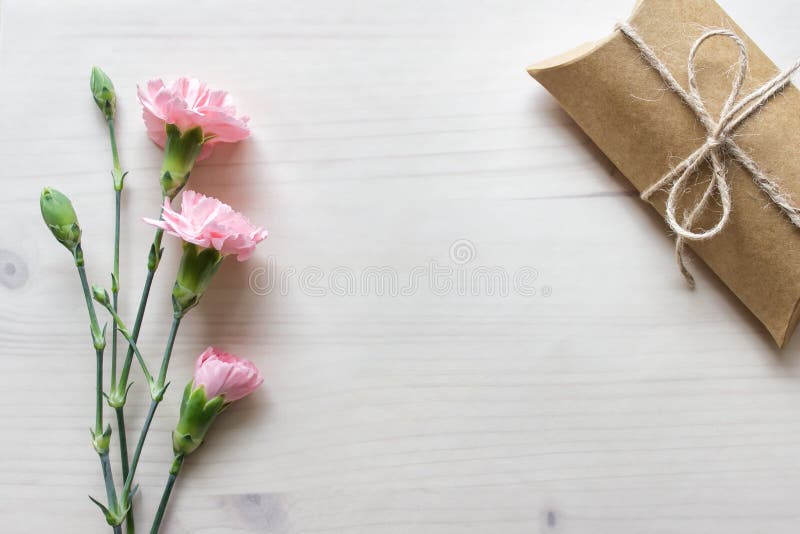 Background with pink flowers, craft paper box present and blank space on wooden background covered with transparent paper. Background with pink flowers, craft paper box present and blank space on wooden background covered with transparent paper