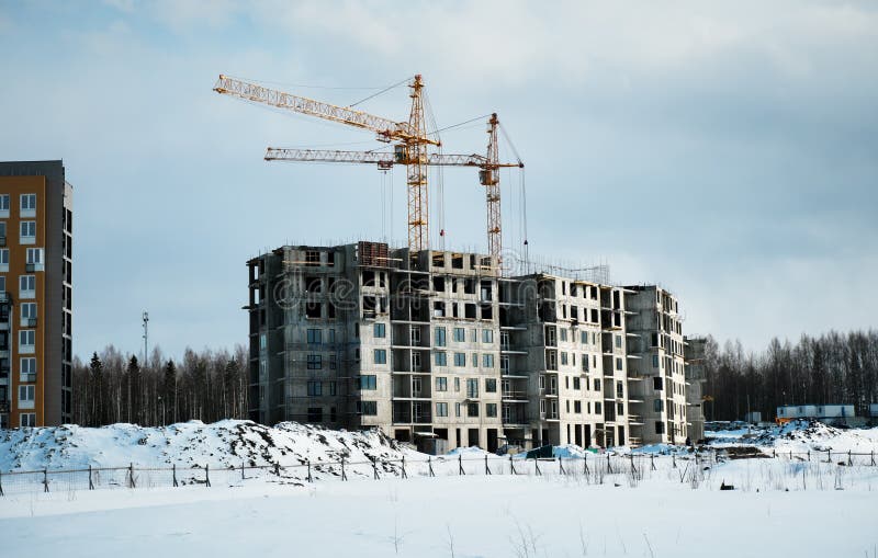 Crane and unfinished house. Building construction in winter. Crane and unfinished house. Building construction in winter.