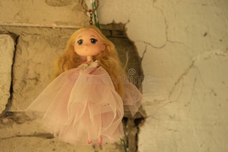 A beautiful antique doll hangs on a ruined wall of an abandoned house. Concept - mysticism, horrors. A beautiful antique doll hangs on a ruined wall of an abandoned house. Concept - mysticism, horrors.