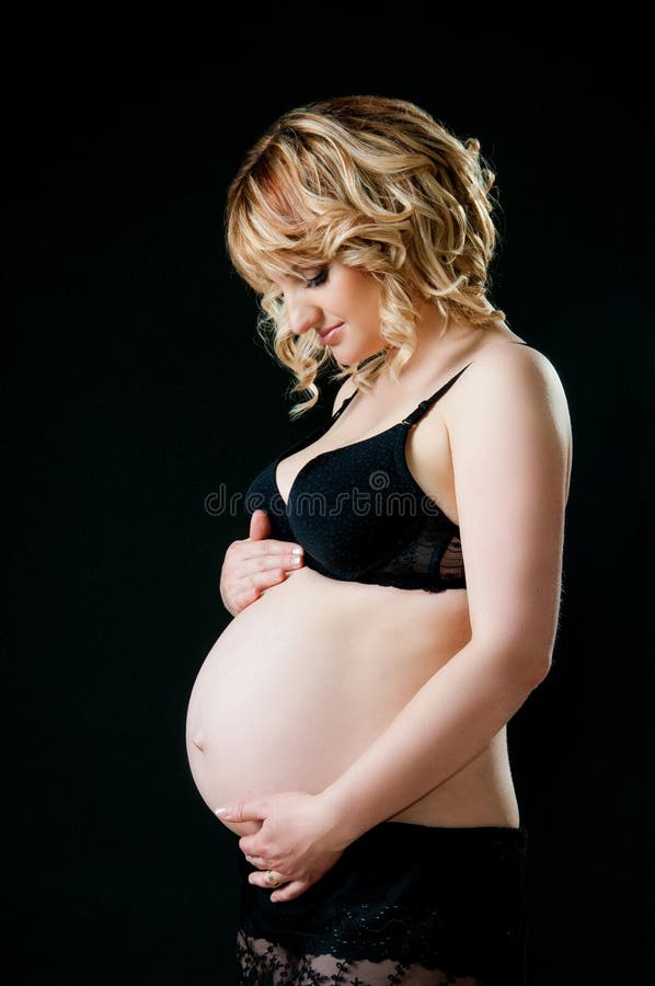 Красивая беременная мать с нежностью смотрит tummy стоковое изображение