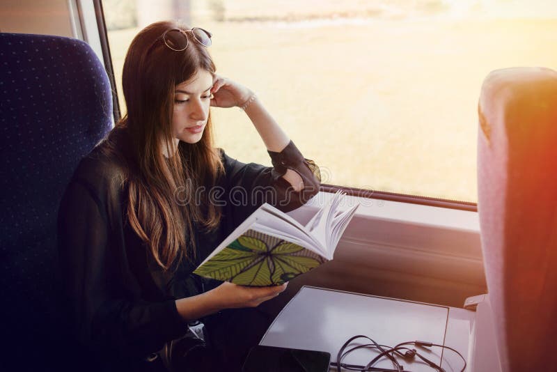 Красивая девушка битника путешествуя поездом и держа книгу Styl стоковое изображение Красивая девушка битника путешествуя поездом и держа книгу Styl стоковое изображение