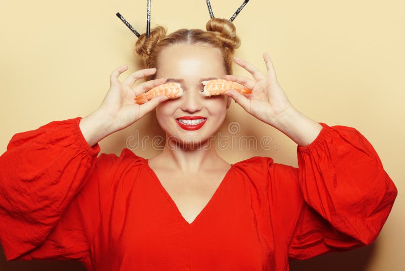 красивая девушка едят суши на белой тарелке. женщина в красном платье и ...