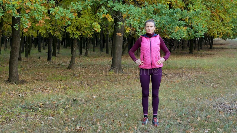 Красивая девушка спорта фитнеса нагревает перед бежать в парке осени Разминка Outdoors