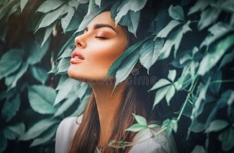 Красивая девушка фотомодели наслаждаться природой дышать свежим воздухом в летнем саду на зеленом фоне листьев стоковая фотография