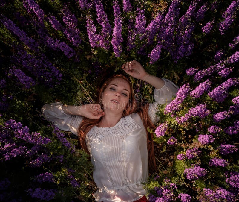 Красивая женщина redhaire с фиолетовыми цветами в поле стоковое фото