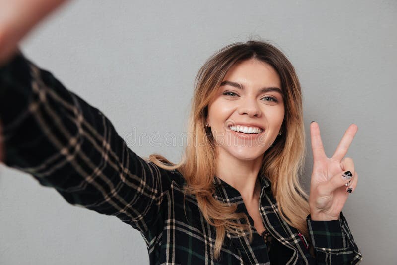 Красивая женщина делая selfie и показывая жест мира с пальцами стоковые изображения rf
