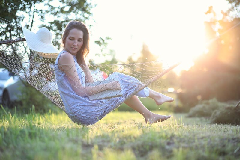 Красивая маленькая девочка лежа и читая книгу в outdoorsr лета