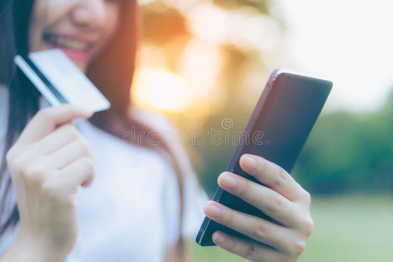 Красивая молодая азиатская женщина используя ее smartphone для того чтобы ходить по магазинам онлайн стоковое изображение rf Красивая молодая азиатская женщина используя ее smartphone для того чтобы ходить по магазинам онлайн стоковое изображение rf