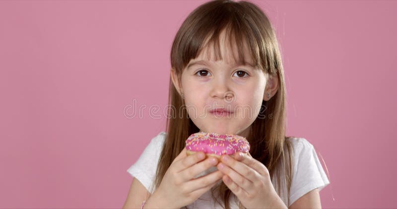 Красивая молодая девушка кавказская уловленная ел сладкого розовый пончик