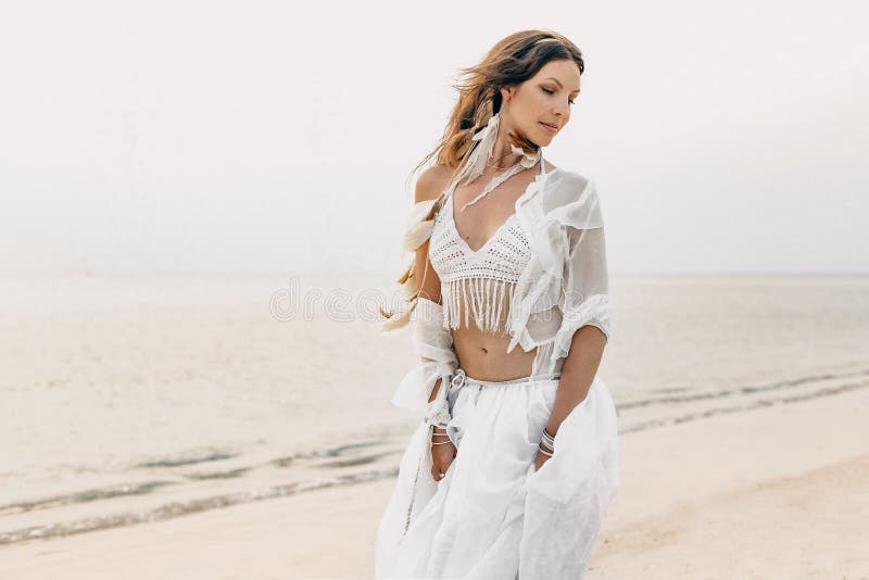 Красивая молодая женщина boho в белом платье и пер представляя дальше стоковая фотография