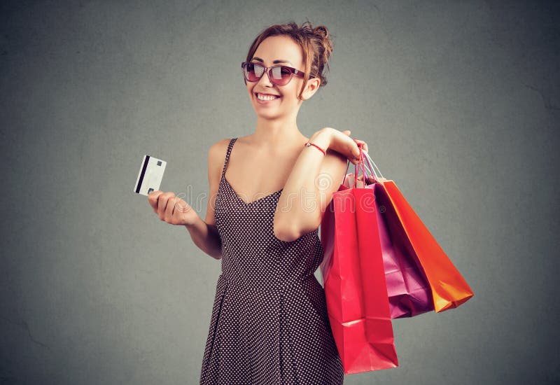 Красивая молодая женщина в солнечных очках с shoppping сумками и кредитной карточкой стоковое изображение