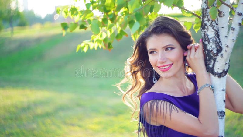 Красивая молодая женщина около деревьев березы в парке