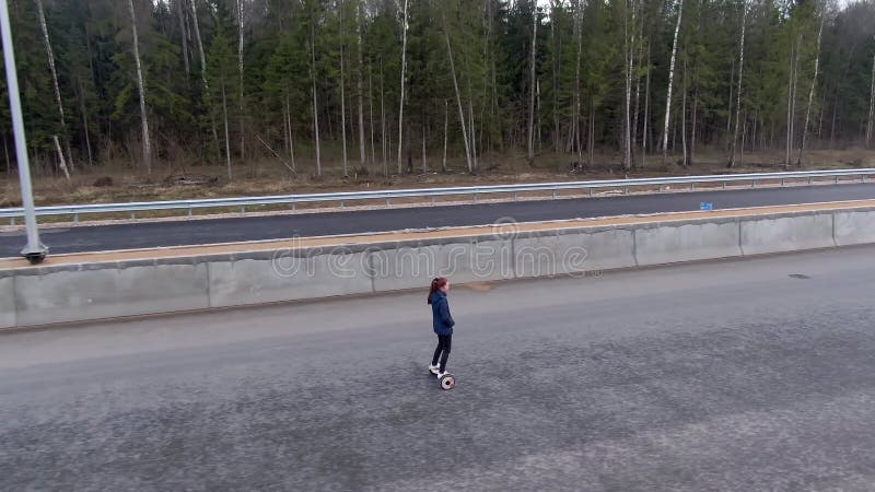 Красивая молодая женщина правит в одиночку на шоссе на hoverboard до заката