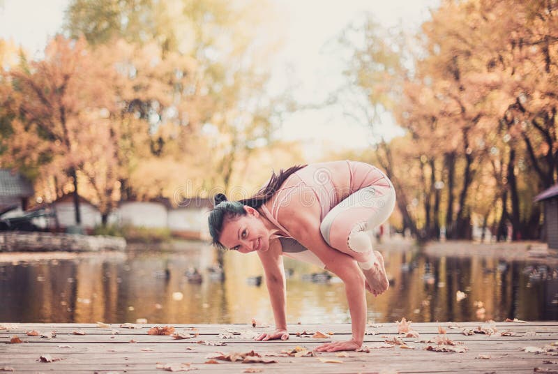 Красивая молодая женщина практикует asana йоги на деревянном столе в парке осени стоковые изображения rf