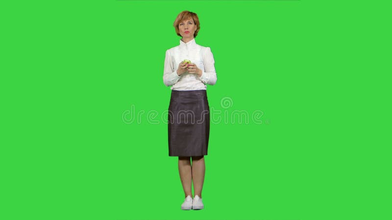 Красивая молодая женщина, съедающая яблоко на зеленом экране, Chroma Key акции видеоматериалы