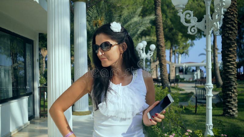 Красивая счастливая молодая женщина принимая фото selfie с умным телефоном outdoors в парк на летний день видеоматериал