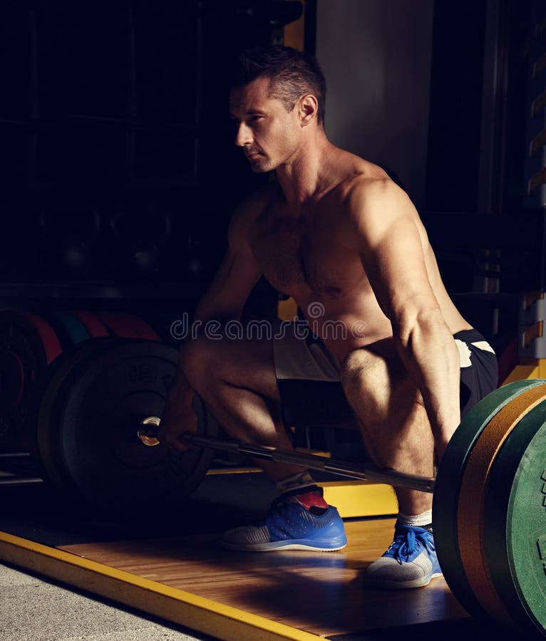 Красивая штанга сильного человека поднимаясь в спортзале crossfit и lookin s стоковые изображения rf Красивая штанга сильного человека поднимаясь в спортзале crossfit и lookin s стоковые изображения rf