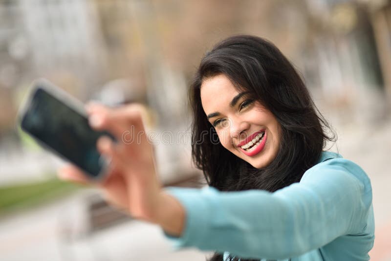 Portrait of a beautiful young woman, using braces, selfie in the street with a smartphone. Portrait of a beautiful young woman, using braces, selfie in the street with a smartphone