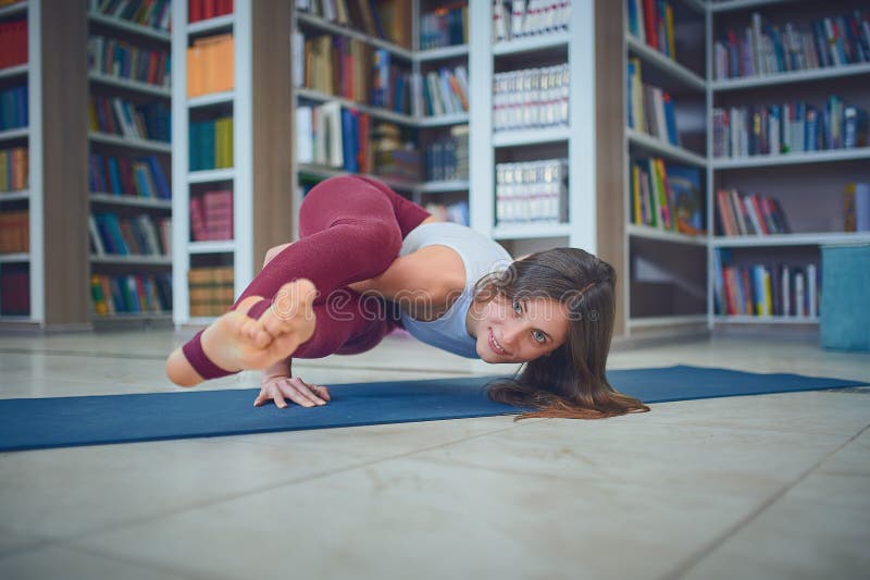 Красивое представление Ashtavakrasana asana йоги handstand практик женщины в библиотеку стоковое фото Красивое представление Ashtavakrasana asana йоги handstand практик женщины в библиотеку стоковое фото
