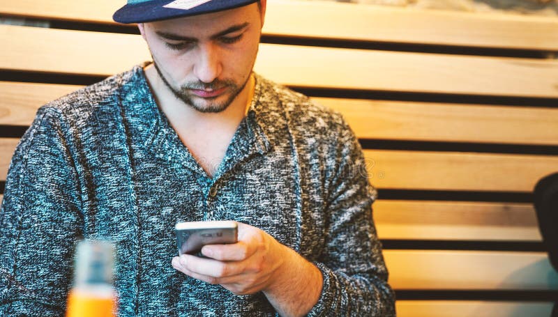 Красивые sms молодого человека отправляя СМС используя app на smartphone стоковые фотографии rf Красивые sms молодого человека отправляя СМС используя app на smartphone стоковые фотографии rf