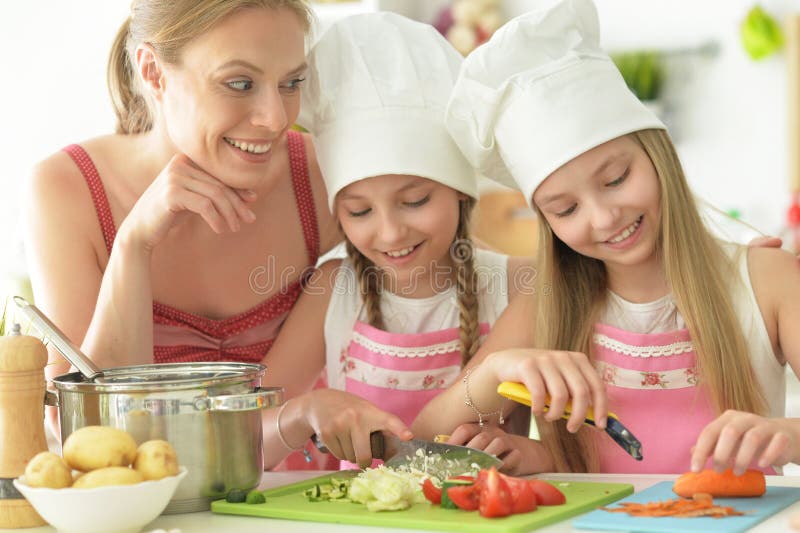Красивые девушки с матерью, готовя вкуснейший свежий салат на кухне стоковые изображения