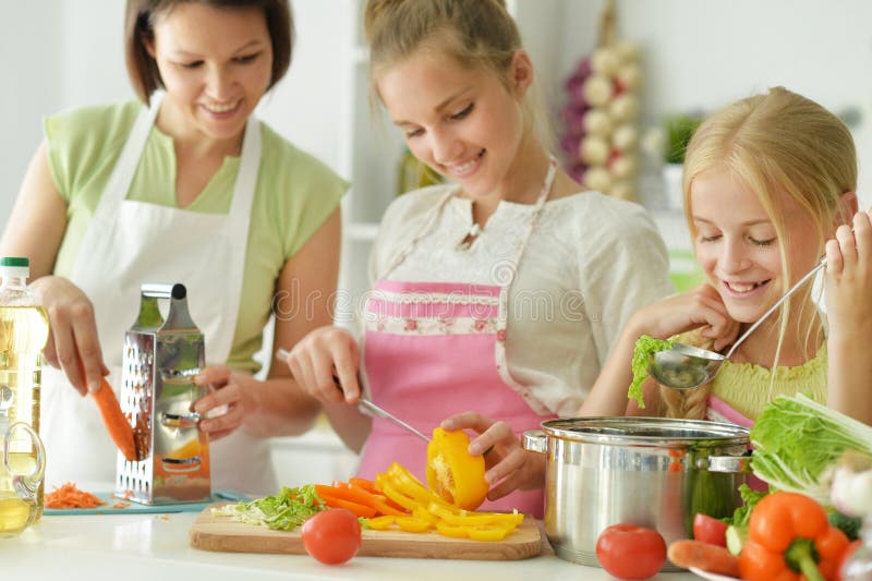 Красивые девушки с матерью, готовя вкуснейший свежий салат на кухне стоковые фотографии rf