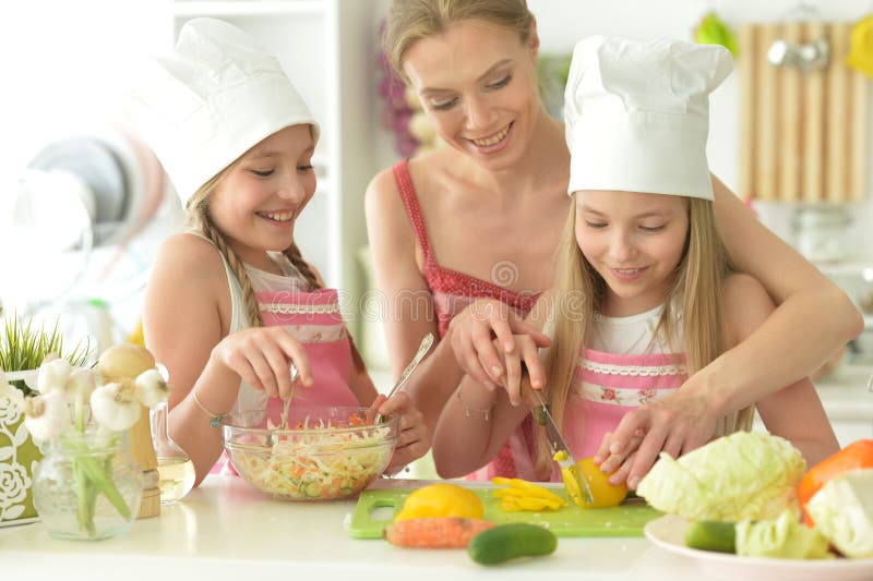 Красивые девушки с матерью, готовя вкуснейший свежий салат на кухне стоковая фотография