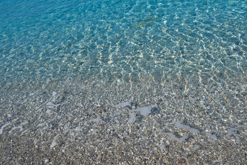 Красивые красочные камешки и большой камень под чистой водой сини бирюзы, сценарной морской предпосылкой или текстурой, взглядом стоковое фото rf Красивые красочные камешки и большой камень под чистой водой сини бирюзы, сценарной морской предпосылкой или текстурой, взглядом стоковое фото rf
