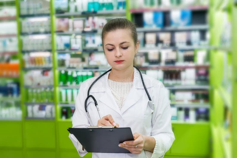 Красивый apothecary проверяя список лекарства на планшете стоковая фотография rf Красивый apothecary проверяя список лекарства на планшете стоковая фотография rf