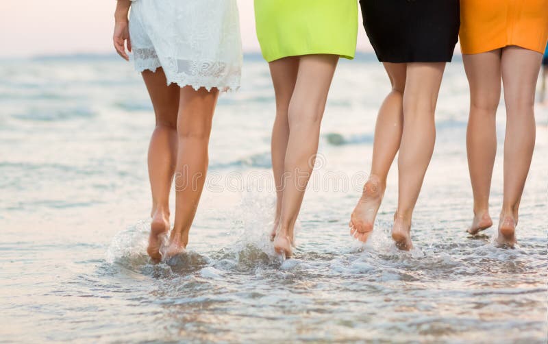 Adorable long-legged girls walk near the sea on the sand. Long and smooth female legs on the background of the sea, view from back. Close-up of a cute sports women`s legs. Beautiful girls on a tropical beach sea. Adorable long-legged girls walk near the sea on the sand. Long and smooth female legs on the background of the sea, view from back. Close-up of a cute sports women`s legs. Beautiful girls on a tropical beach sea.