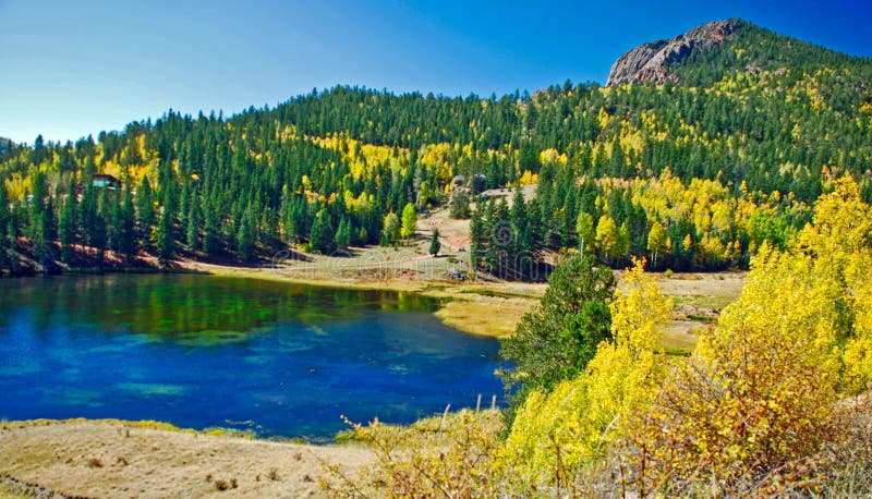 This is a perfect fall day in the Rocky Mountains replete with a lake, pines and aspens turning yells in the fall. This is a perfect fall day in the Rocky Mountains replete with a lake, pines and aspens turning yells in the fall
